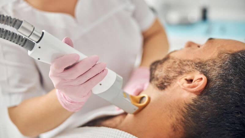 man lying down having laser hair removal on sideburns by specialist – What Is A Small Area For Laser Hair Removal